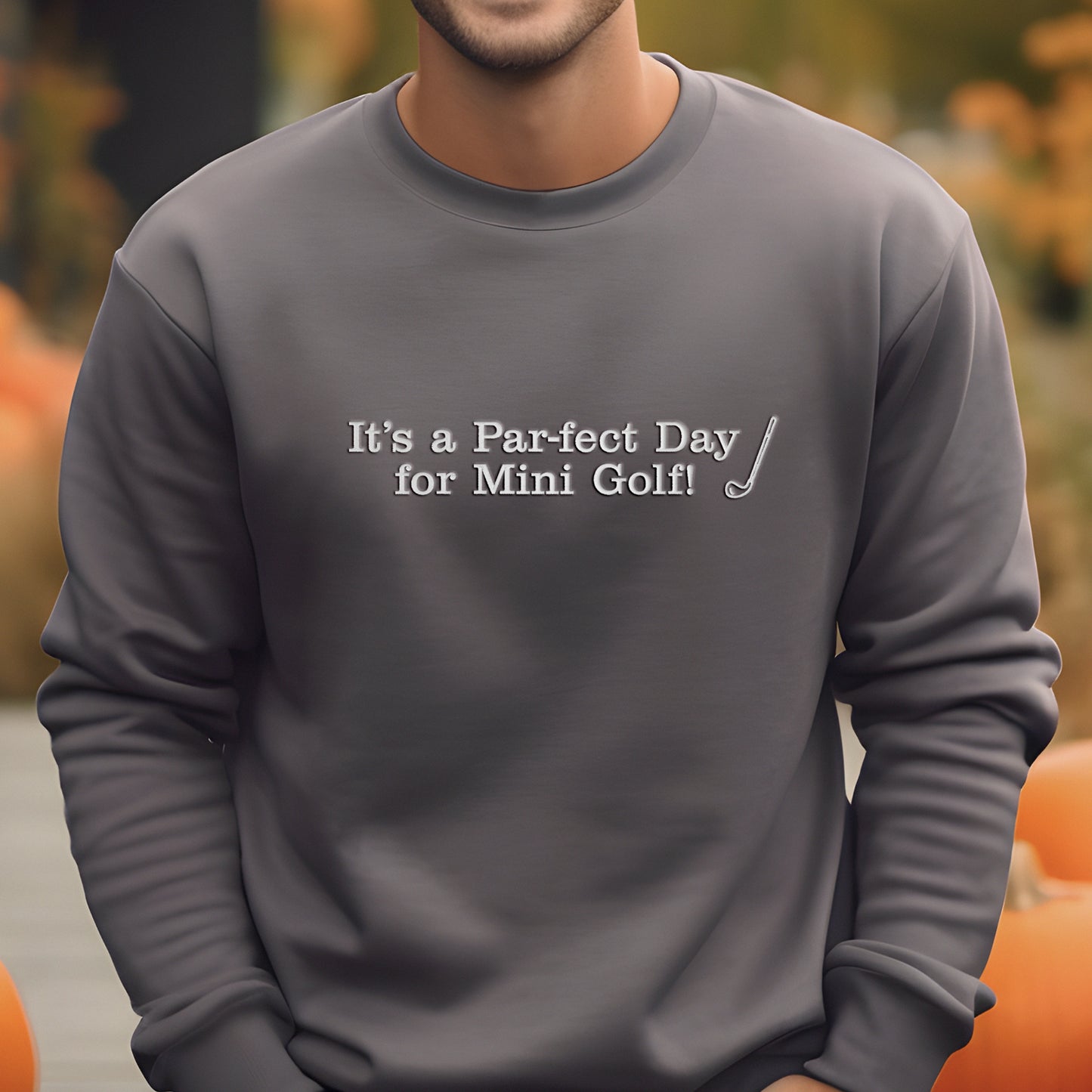 A man wearing a gray sweatshirt with the text "It's a Par-fect Day for Mini Golf!" printed on it.