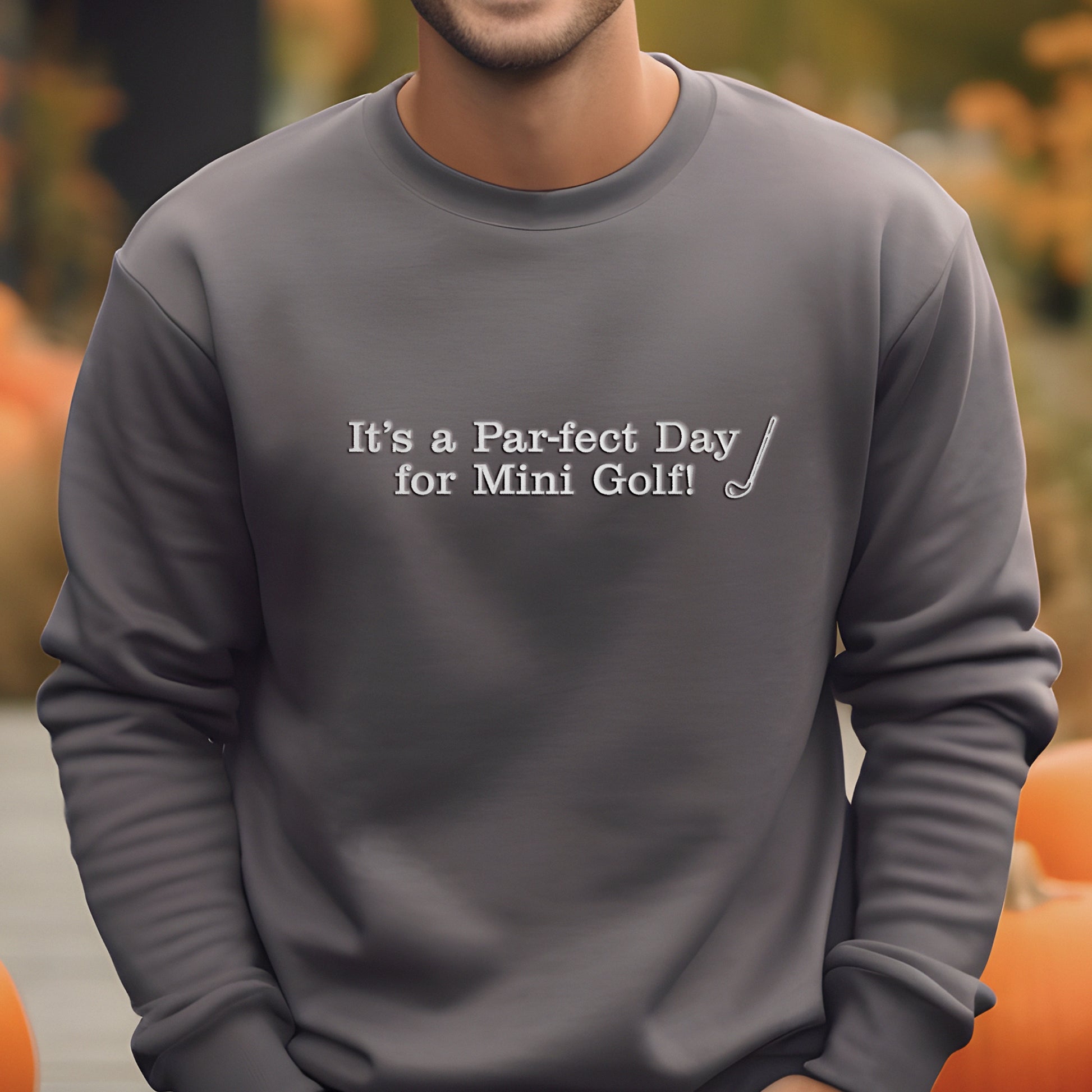 A man wearing a gray sweatshirt with the text "It's a Par-fect Day for Mini Golf!" printed on it.