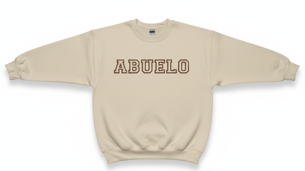 A beige sweatshirt with the word "abuela" embroidered on the front in bronze thread